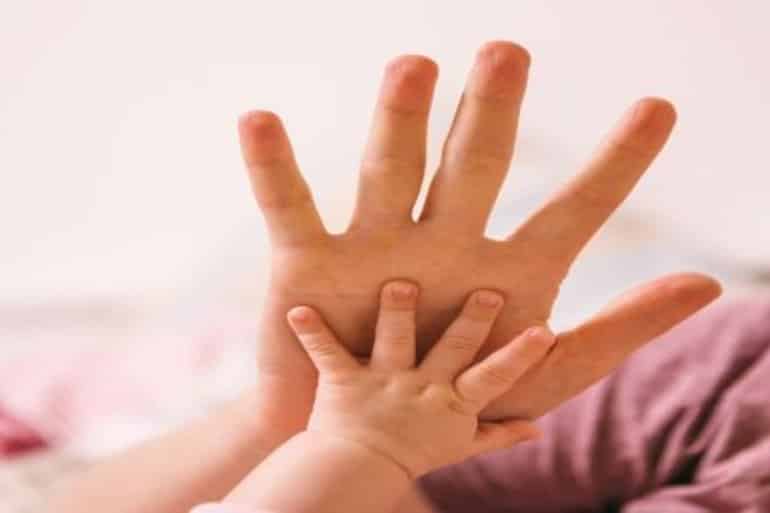 This shows a baby touching an adult's hand