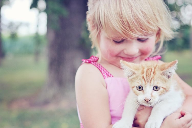 Image shows a girl hugging a cat.