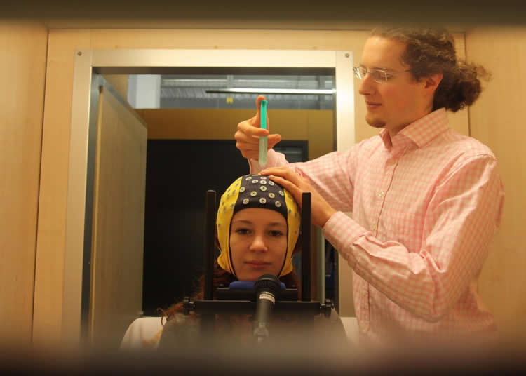 Image shows a woman in an EEG cap.