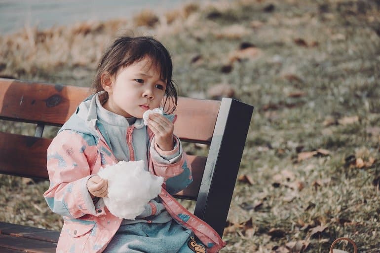 This shows a little girl eating cotton candy