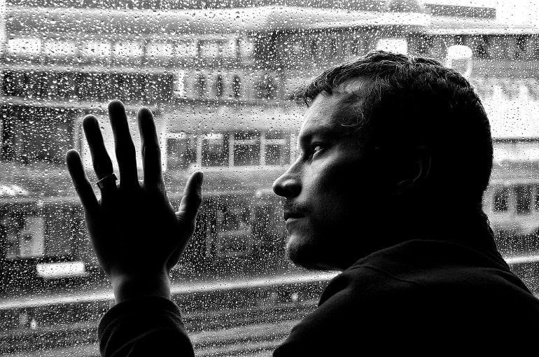This shows a depressed man looking out of a window