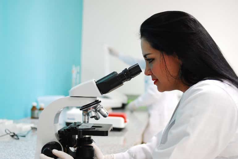 This shows a female scientist looking in a microscope