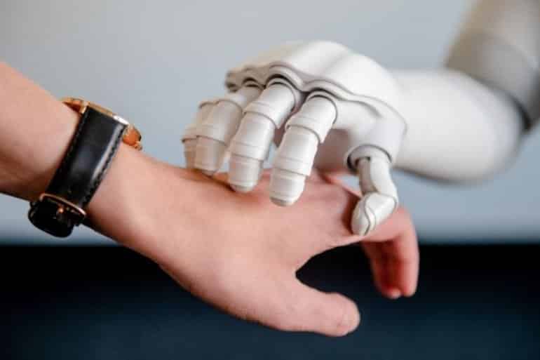 This shows a robot hand resting on top of a person's hand